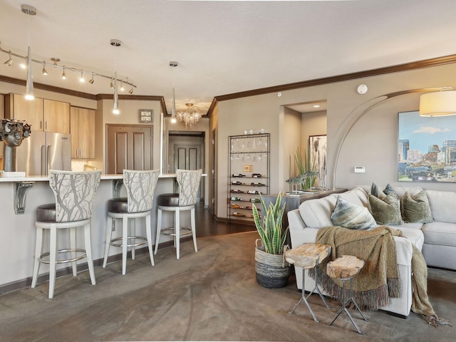 carpeted living room with crown molding, an inviting chandelier, and rail lighting