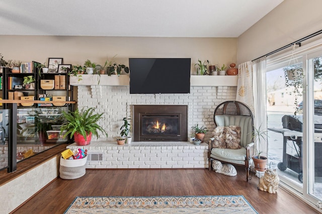 living room with a brick fireplace and dark hardwood / wood-style floors