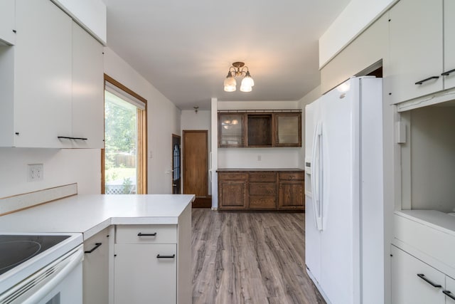 kitchen with white fridge with ice dispenser, a chandelier, white cabinetry, kitchen peninsula, and light hardwood / wood-style flooring