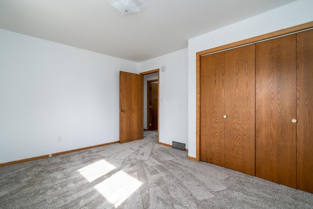 unfurnished bedroom featuring light carpet and a closet