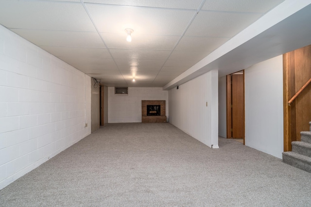 basement with a paneled ceiling, a fireplace, and light colored carpet