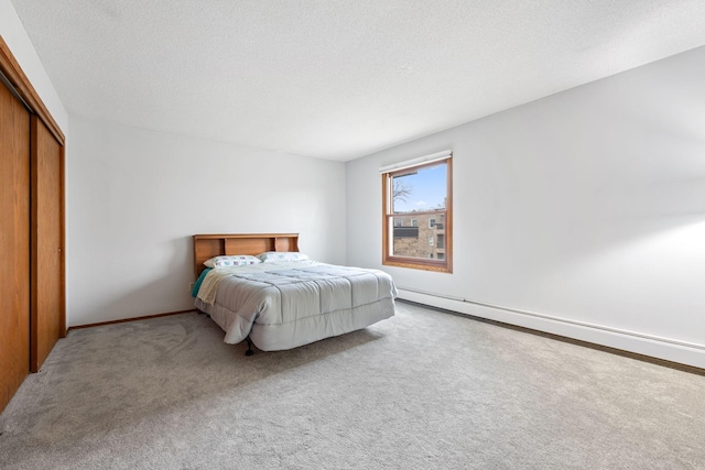 carpeted bedroom featuring a textured ceiling, a baseboard radiator, and a closet