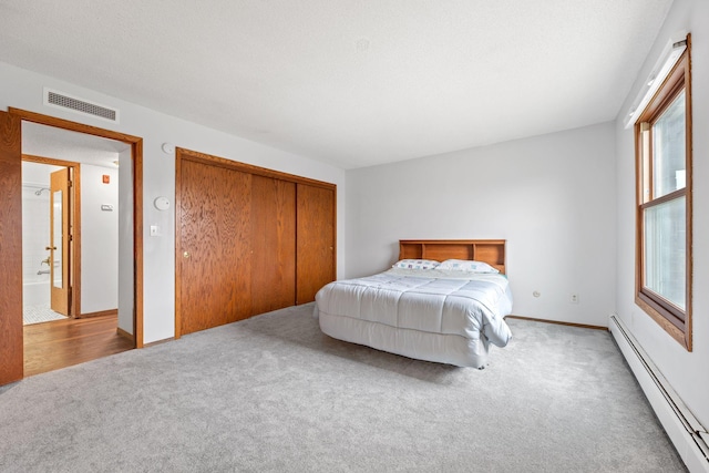 bedroom featuring carpet flooring, a closet, and a baseboard heating unit