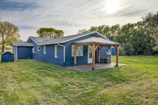 rear view of house featuring a yard, a storage unit, and a patio area