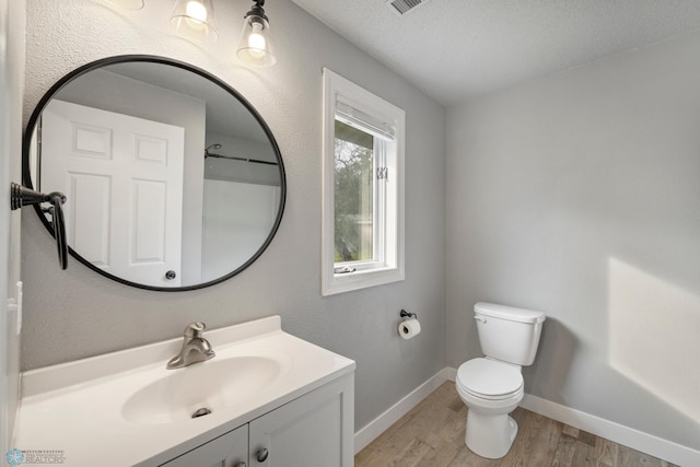 bathroom featuring vanity, hardwood / wood-style floors, toilet, and a textured ceiling