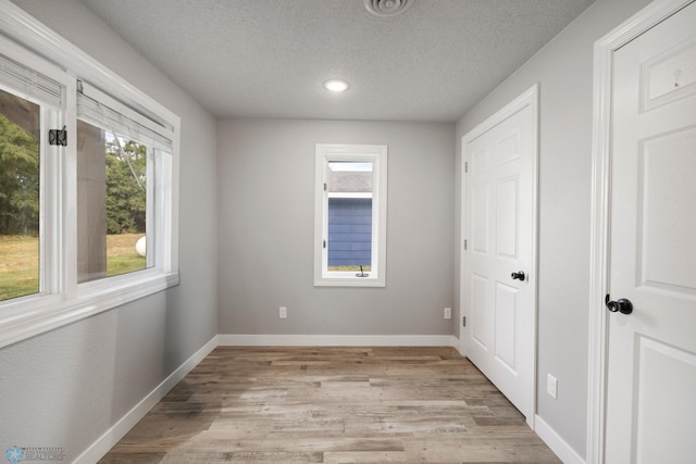 empty room with light hardwood / wood-style flooring and a textured ceiling