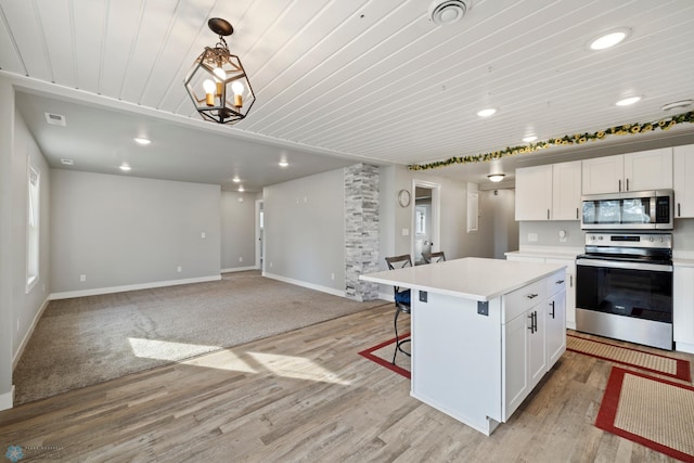 kitchen featuring white cabinets, stainless steel appliances, light wood-type flooring, and a kitchen island