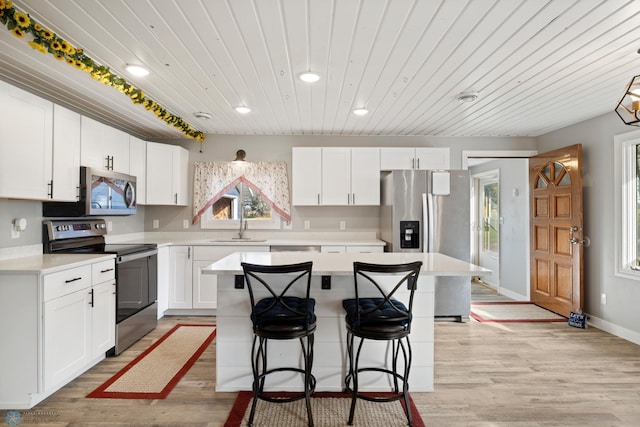 kitchen featuring stainless steel appliances, white cabinets, light hardwood / wood-style floors, and a kitchen island