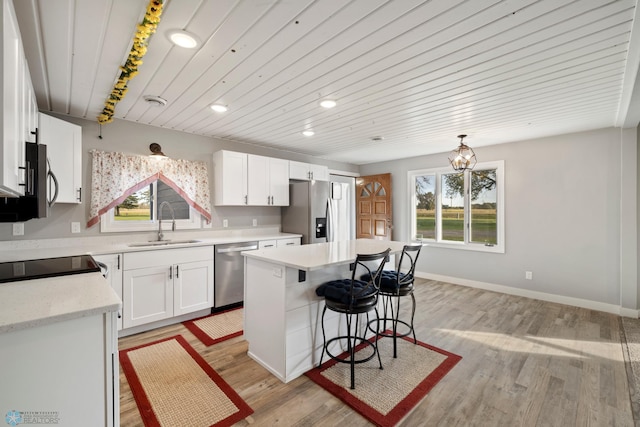 kitchen featuring stainless steel appliances, white cabinets, plenty of natural light, and a kitchen island