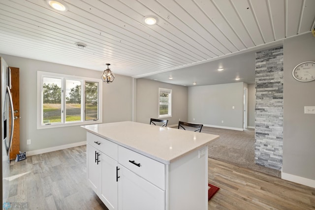 kitchen featuring white cabinets, light hardwood / wood-style flooring, wood ceiling, and a kitchen island