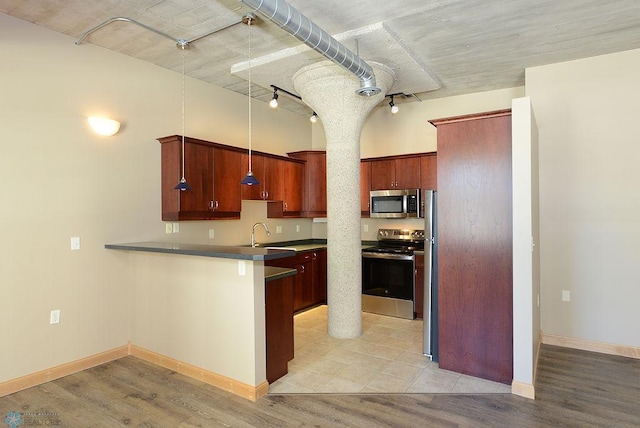 kitchen with pendant lighting, kitchen peninsula, appliances with stainless steel finishes, and light hardwood / wood-style flooring