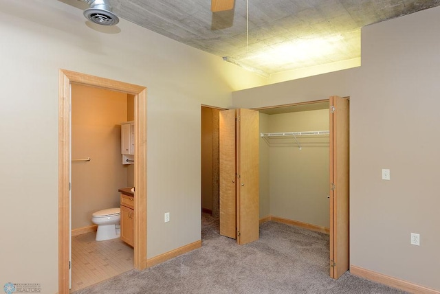 unfurnished bedroom featuring ceiling fan, connected bathroom, a closet, and light carpet