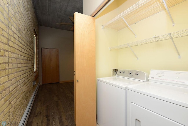 washroom featuring baseboard heating, brick wall, dark wood-type flooring, and washing machine and dryer