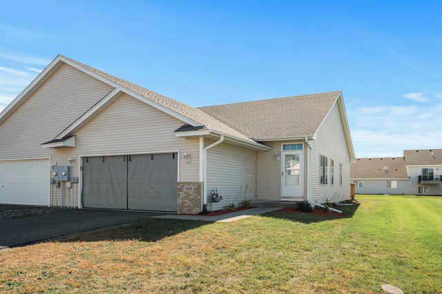 view of front of property featuring aphalt driveway, an attached garage, brick siding, roof with shingles, and a front yard