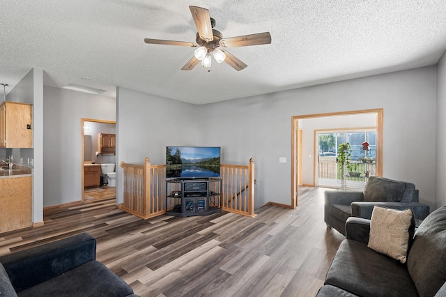 living area with a ceiling fan, a textured ceiling, baseboards, and wood finished floors