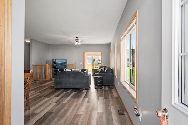 living room with ceiling fan, wood finished floors, visible vents, and baseboards