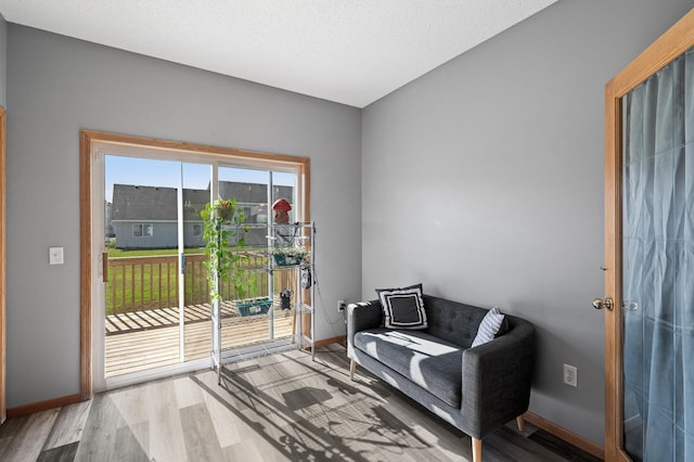 living area featuring light wood-type flooring, baseboards, and a textured ceiling