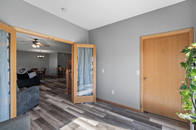 interior space with dark wood-type flooring, baseboards, and ceiling fan with notable chandelier