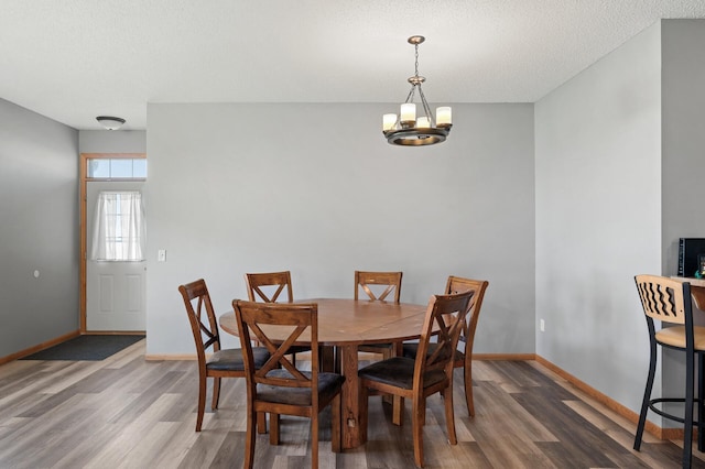 dining room with a notable chandelier, baseboards, and dark wood-style flooring