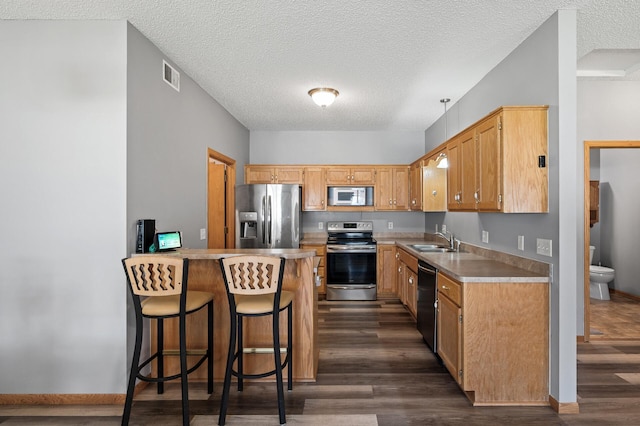 kitchen featuring dark wood-style floors, stainless steel appliances, light countertops, visible vents, and a sink