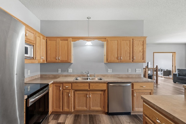 kitchen featuring light countertops, appliances with stainless steel finishes, a sink, and dark wood finished floors