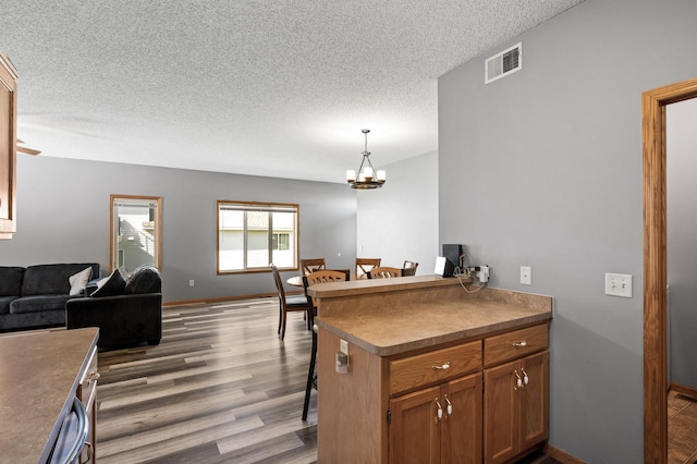 kitchen with dark countertops, brown cabinets, open floor plan, decorative light fixtures, and a peninsula