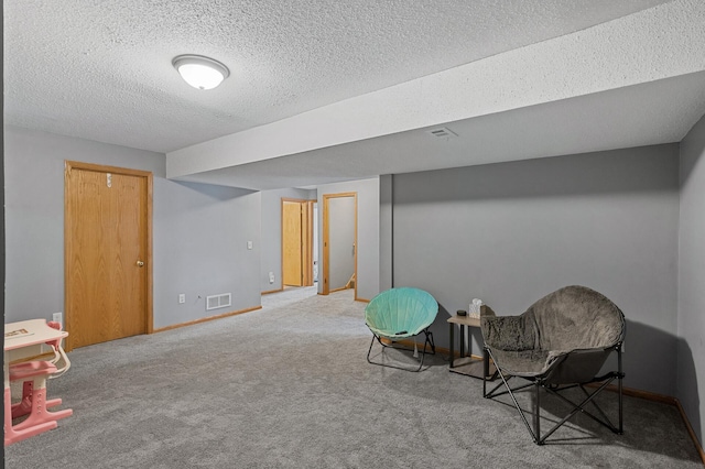 sitting room with carpet floors, baseboards, visible vents, and a textured ceiling