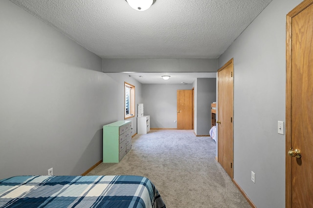 bedroom with light carpet, baseboards, and a textured ceiling