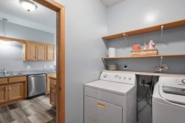 laundry room featuring a textured ceiling, light wood-style flooring, laundry area, a sink, and washer and dryer