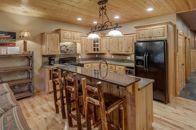 kitchen with light wood-type flooring, black appliances, light brown cabinets, and pendant lighting