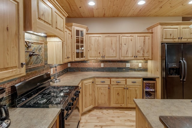 kitchen featuring black appliances, light hardwood / wood-style floors, beverage cooler, and light brown cabinets