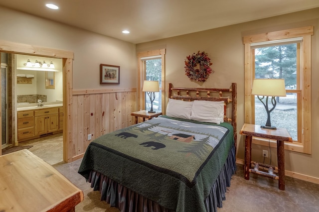 bedroom featuring multiple windows, connected bathroom, and light colored carpet