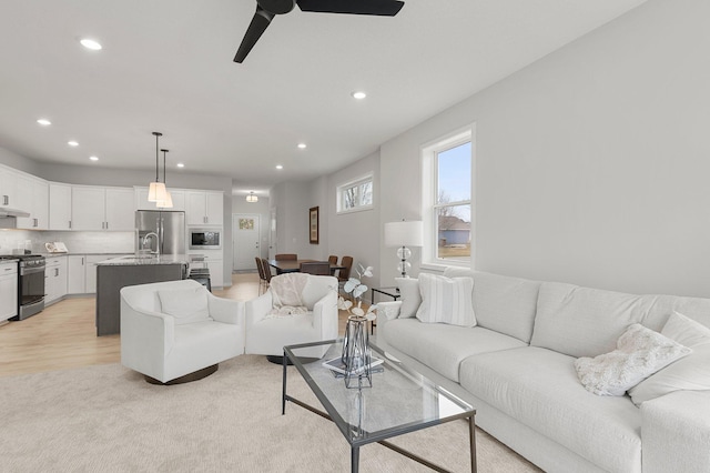 living room with ceiling fan, light wood-type flooring, and sink