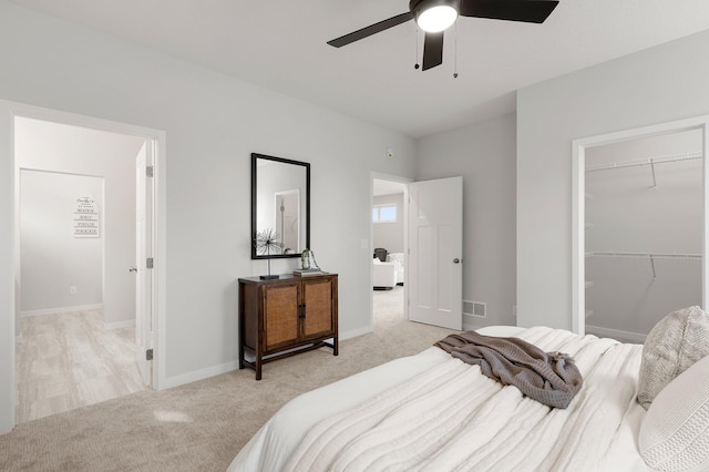 bedroom with ceiling fan, a closet, light carpet, and a spacious closet