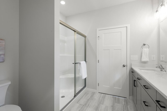 bathroom with walk in shower, vanity, toilet, and wood-type flooring