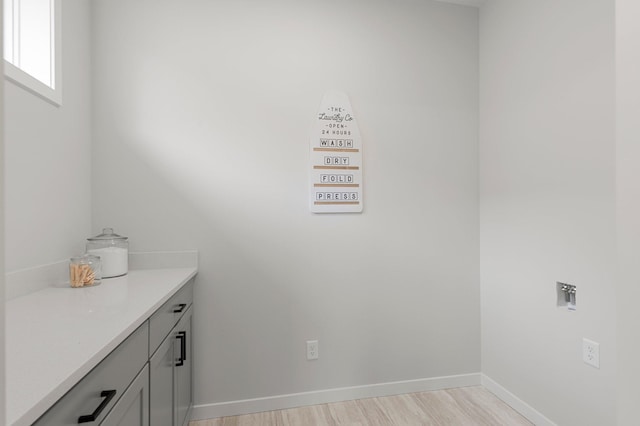 washroom with washer hookup, light hardwood / wood-style floors, and cabinets