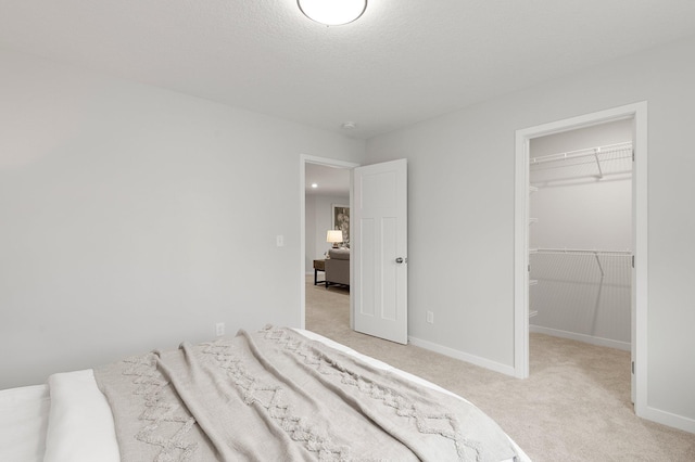 carpeted bedroom featuring a closet, a walk in closet, and a textured ceiling