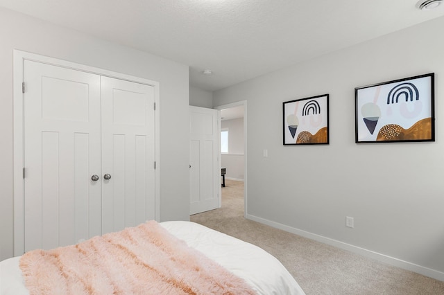 bedroom featuring light colored carpet and a closet