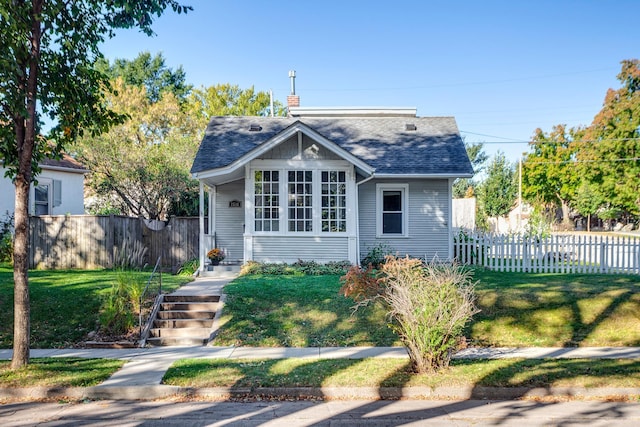 bungalow featuring a front yard, roof with shingles, fence, and a chimney