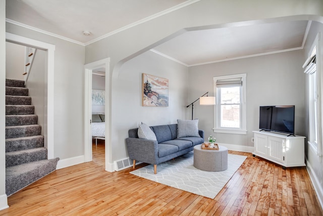 living area featuring hardwood / wood-style flooring, baseboards, stairway, and ornamental molding