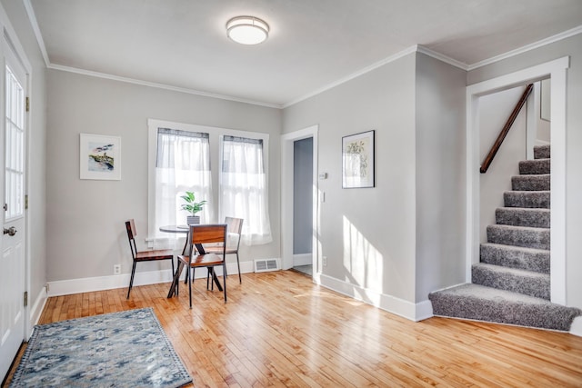 dining space with ornamental molding, wood-type flooring, visible vents, and stairway