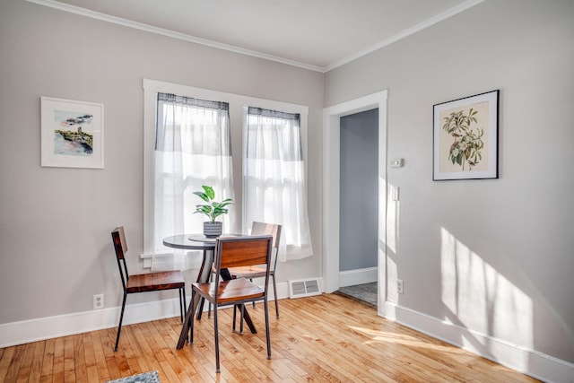 dining room featuring ornamental molding, visible vents, light wood-style flooring, and baseboards