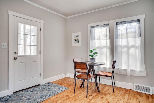 dining room featuring hardwood / wood-style floors, baseboards, visible vents, and crown molding