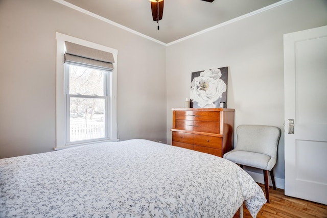 bedroom with ceiling fan, crown molding, baseboards, and wood finished floors