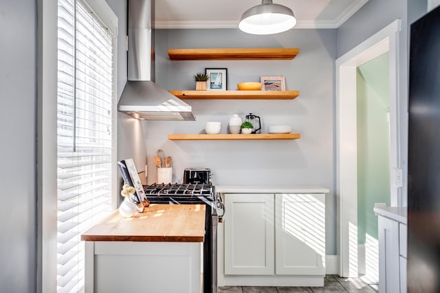 interior space with crown molding, open shelves, white cabinets, stainless steel gas range, and wall chimney exhaust hood