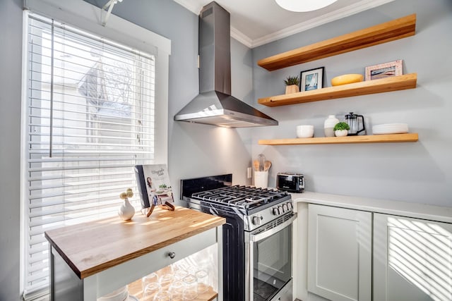 kitchen with butcher block counters, ornamental molding, wall chimney range hood, stainless steel range with gas cooktop, and open shelves