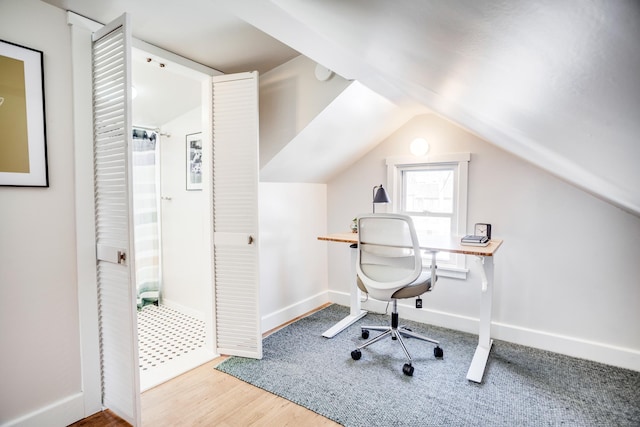 office space with lofted ceiling, baseboards, and wood finished floors