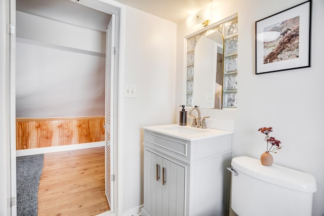 bathroom with wooden walls, wainscoting, toilet, wood finished floors, and vanity