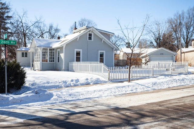 view of front facade with a fenced front yard, an outbuilding, a chimney, and a garage