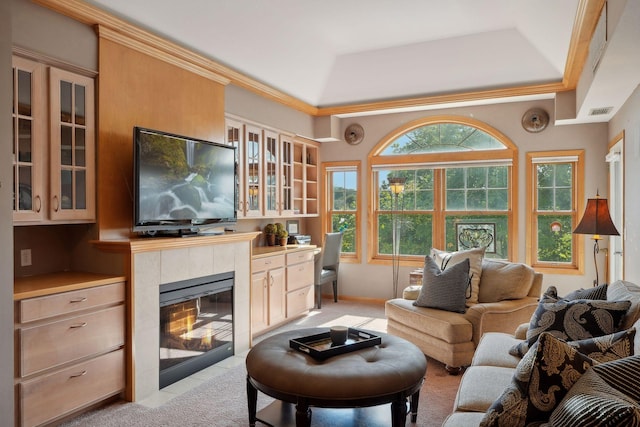 carpeted living room with a tiled fireplace, ornamental molding, and a tray ceiling